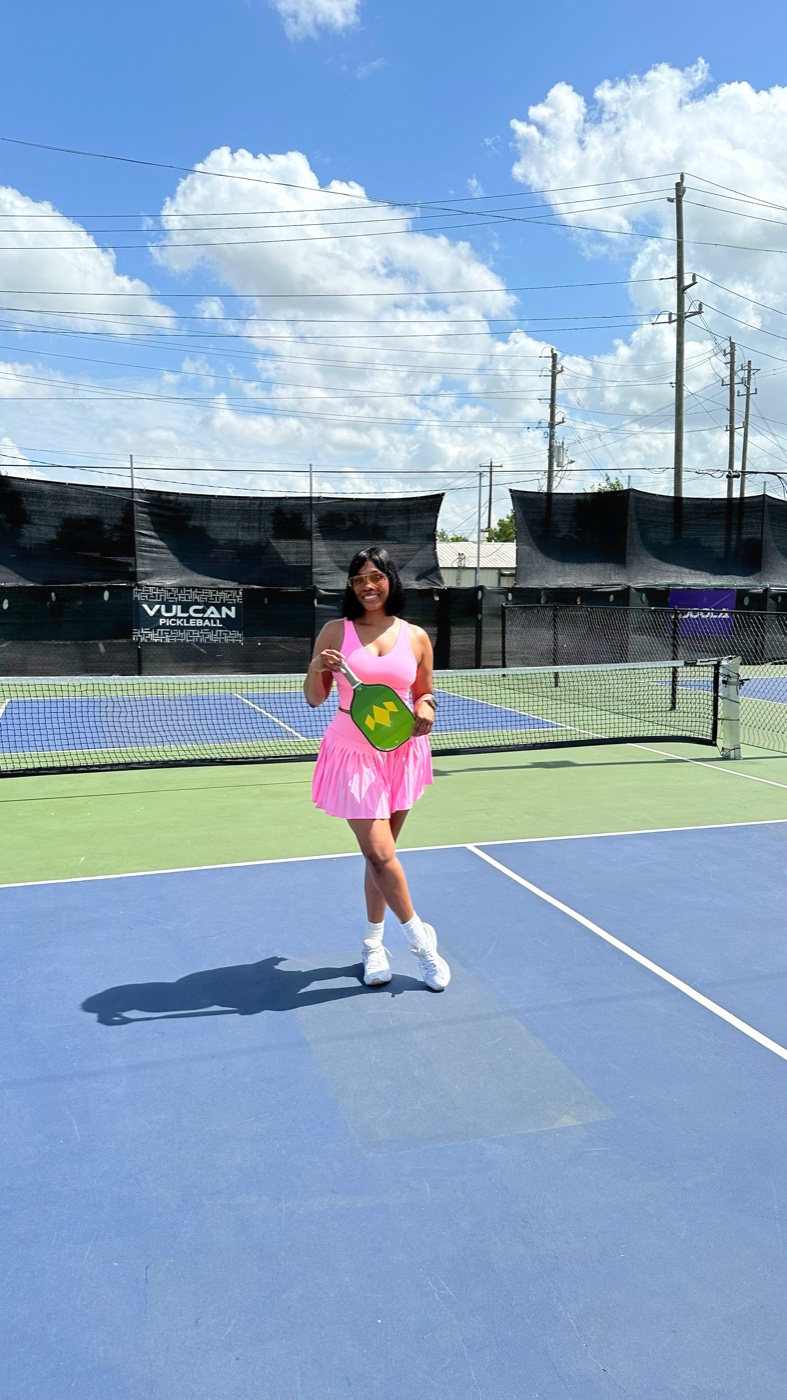Vanessa in a pink outfit playing pickleball on a sunny court